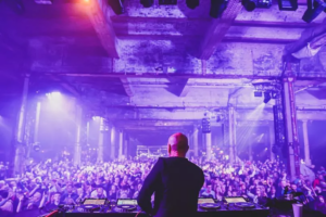 A photo of a DJ looking out over a crowd at The Warehouse Project, a world-famous club night held at Mayfield Depot in Piccadilly, Manchester. 